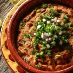 Bowl of authentic refried beans served with tortillas and garnished with cilantro