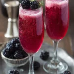 Glass of Blackberry Mimosas garnished with fresh blackberries and mint