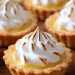 Lemon meringue tartlets topped with fluffy meringue and lemon zest