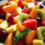 Colorful bowl of fresh fruit salad with berries, melons, and citrus fruits.